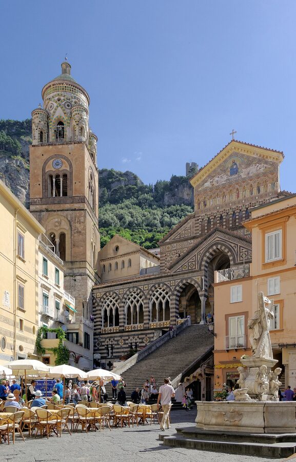 Amalfi seen from above, with the Duomo bell tower rising above the tightly packed white-and-yellow buildings