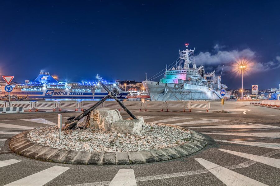 Ancona's port at night with the large anchor monument and ship lights reflecting in the water