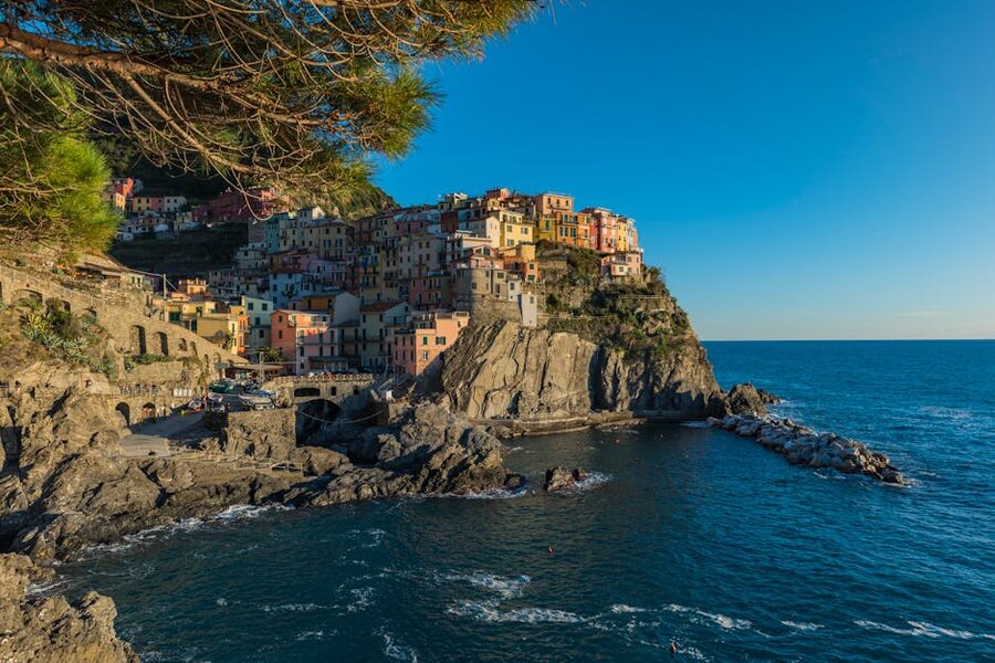 Manarola at sunset with pastel houses stacked above the Ligurian Sea and terraced vineyards in the hills