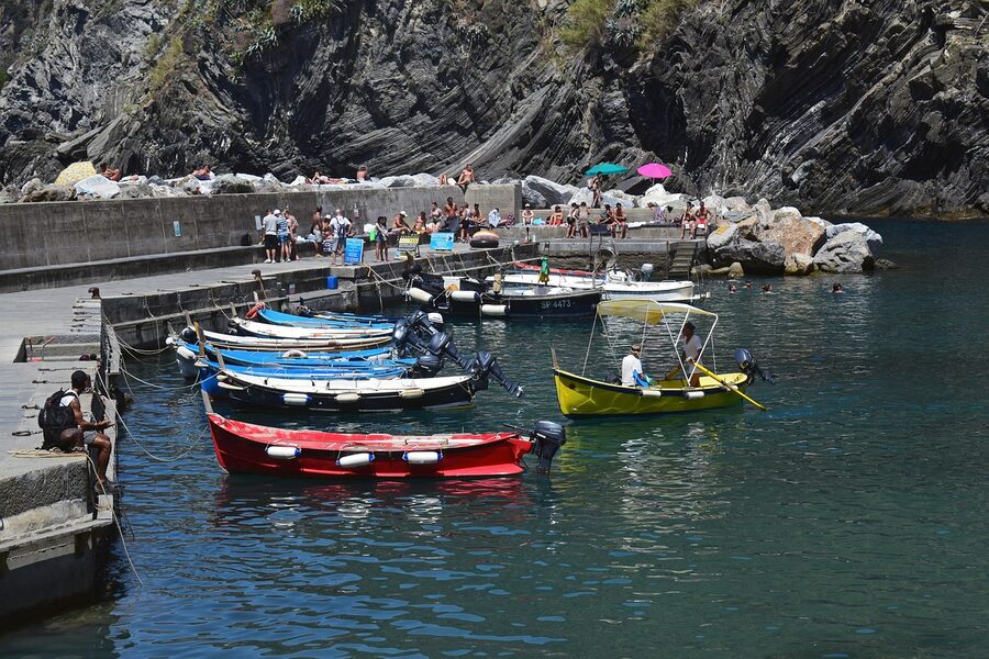 Vernazza harbour with colourful fishing boats, a small piazza and pastel houses stacked up the hillside