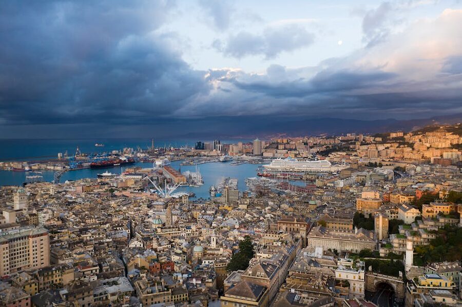 Genoa from the air at dusk showing the port, the harbour curve, and the city climbing up the hillside