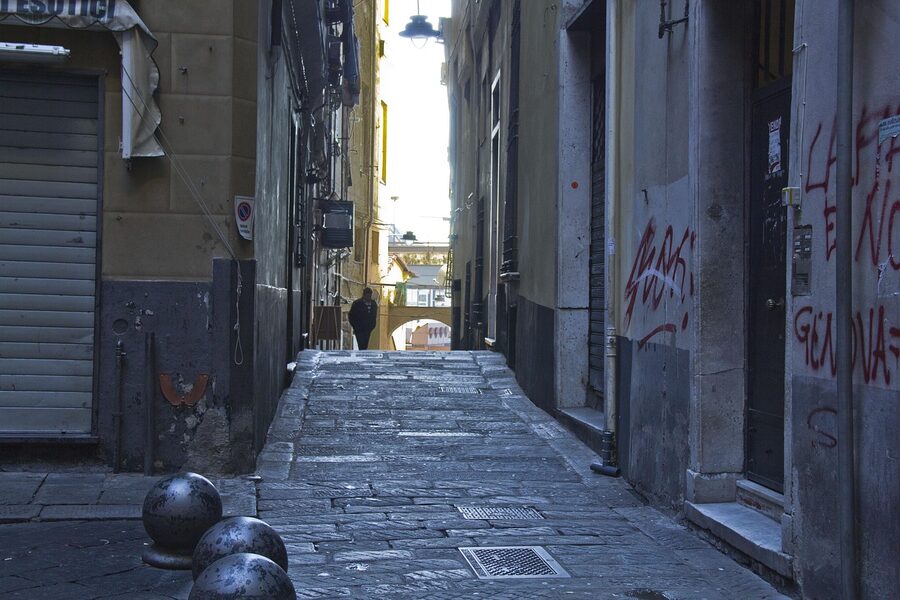 A narrow alleyway in the caruggi medieval old town of Genoa with tall buildings closing out the sky