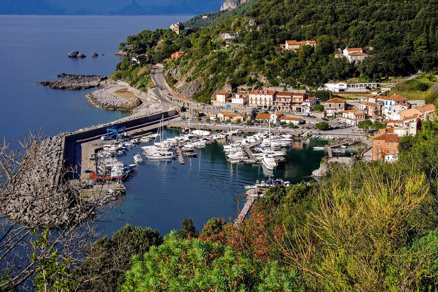 Panoramic view of Porto di Maratea with fishing boats and pastel houses against a blue Tyrrhenian sea