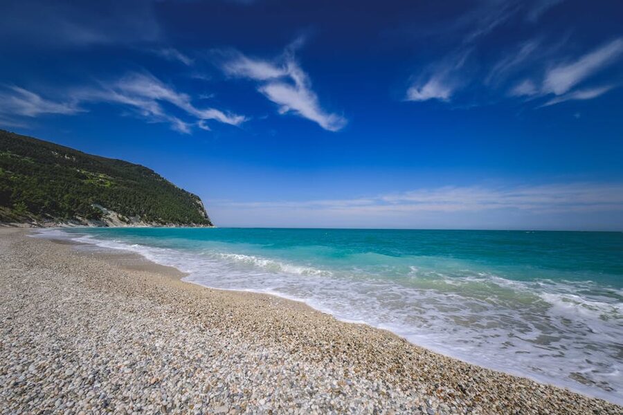 The pebble beach of Spiaggia San Michele on the Conero Riviera with turquoise Adriatic water and white cliffs