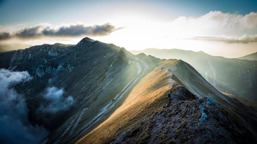 The Sibillini mountains at sunrise with golden light over snow-capped peaks and high grassland