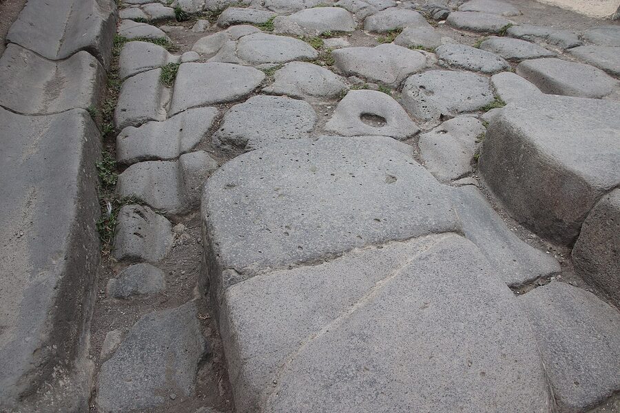 Roman stepping stones on a Pompeii street — the raised stones that let pedestrians cross above the waste-filled road