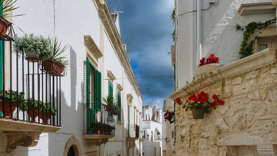 Ostuni's whitewashed streets with vibrant flowers and balconies