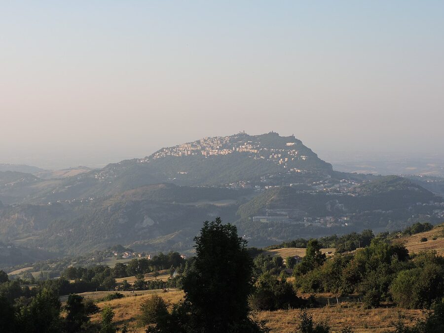 San Marino at sunset seen from Monte San Paolo, with the three towers silhouetted against a golden sky