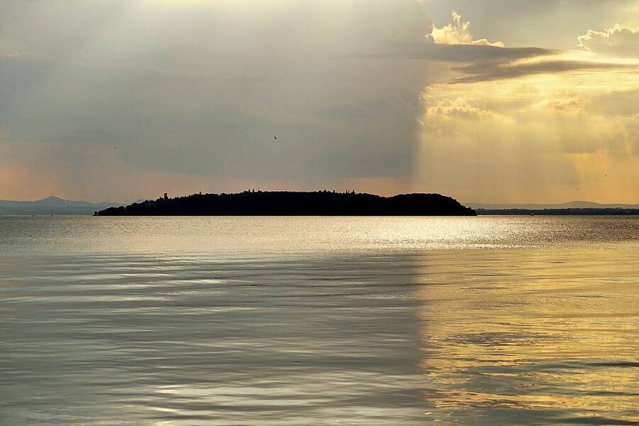 Lake Trasimeno at sunset with silhouetted islands and fishermen's boats