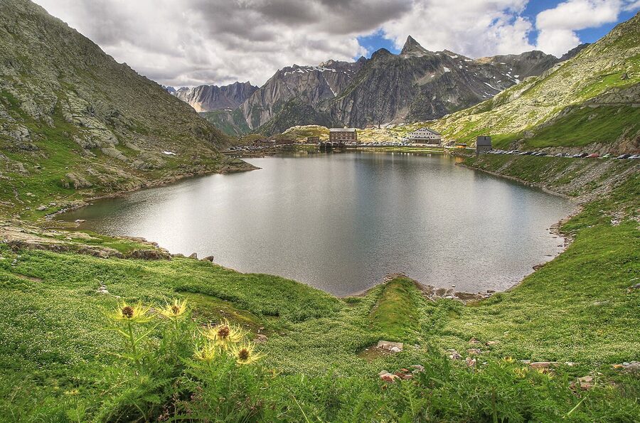 The lake at the top of the Great St Bernard Pass in summer, with hospice buildings and mountain peaks